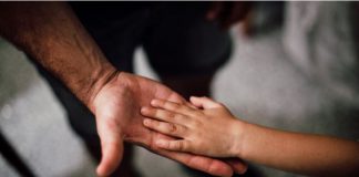 A small child's hand on an adults hand